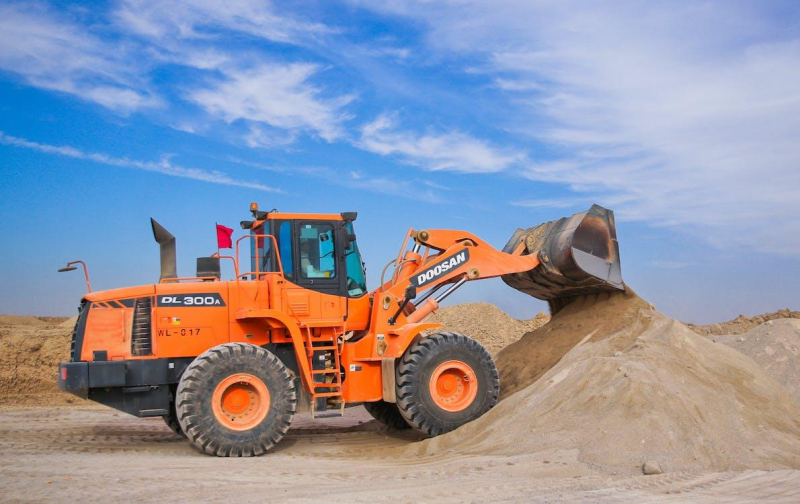 Orange front loader moving sand
